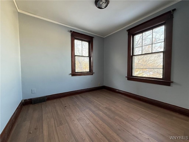 empty room with hardwood / wood-style floors and ornamental molding