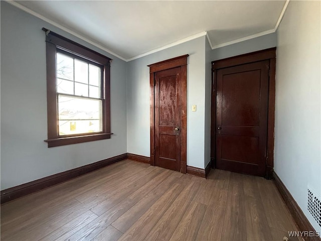 unfurnished bedroom with crown molding and hardwood / wood-style flooring