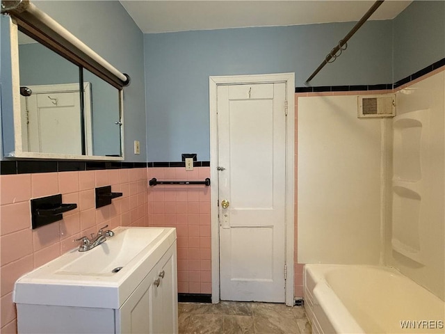 bathroom featuring vanity, shower / washtub combination, and tile walls