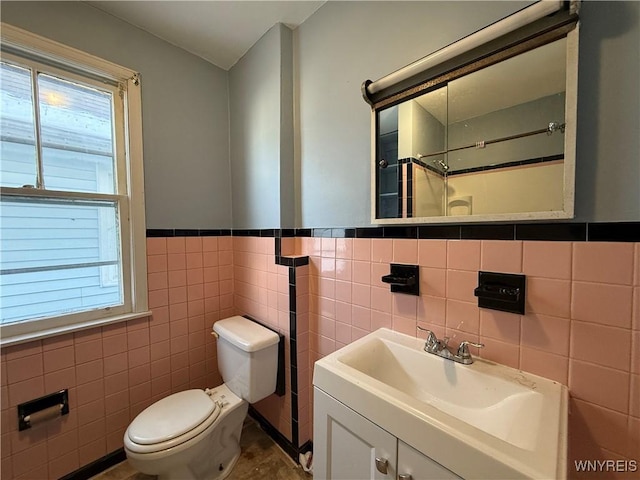 bathroom featuring tile walls, vanity, toilet, and walk in shower