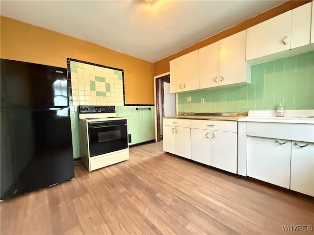 kitchen featuring black refrigerator, white cabinets, and electric stove