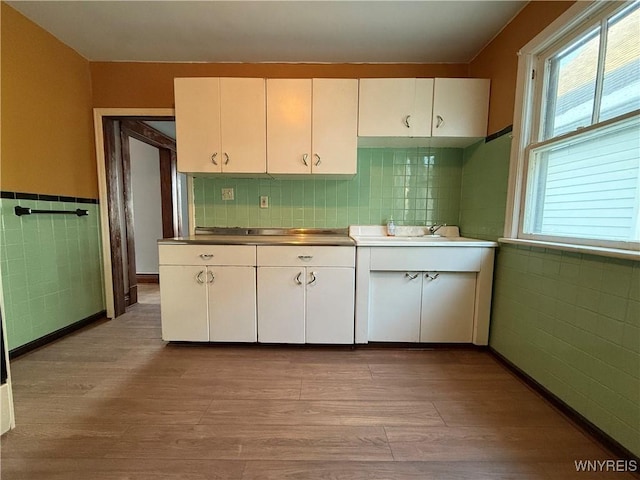 kitchen featuring light hardwood / wood-style floors, tile walls, and white cabinets