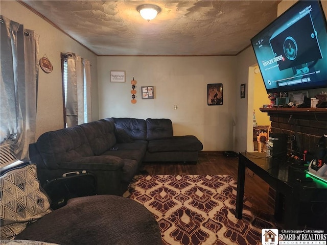 living room with a textured ceiling, a fireplace, ornamental molding, and wood-type flooring