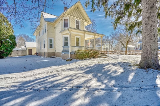 snow covered property with covered porch