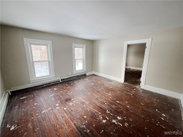 spare room featuring baseboard heating and dark hardwood / wood-style floors