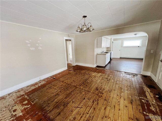 interior space with sink, an inviting chandelier, crown molding, baseboard heating, and dark hardwood / wood-style floors