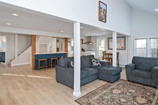 living room featuring sink, a wealth of natural light, high vaulted ceiling, and light wood-type flooring