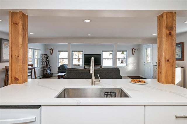 kitchen with light stone counters, sink, and white cabinets