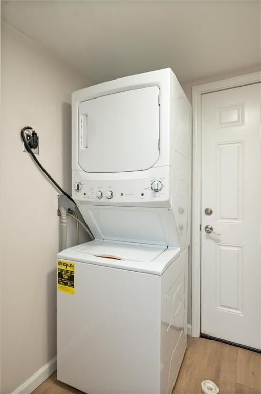 washroom with stacked washer and dryer and light wood-type flooring