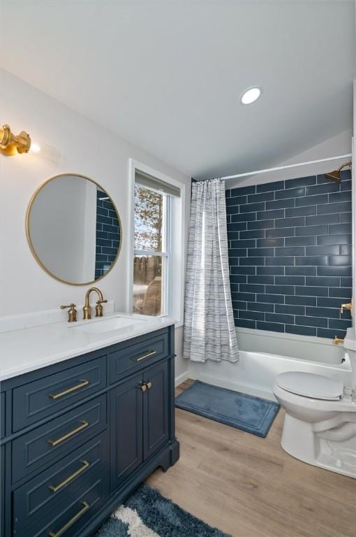 full bathroom featuring wood-type flooring, toilet, shower / bath combo with shower curtain, and vanity