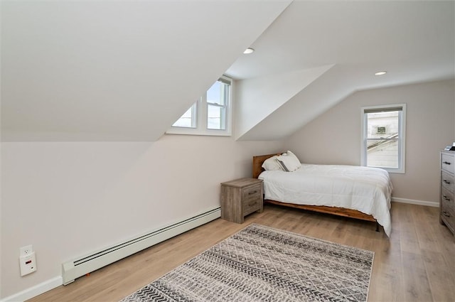 bedroom with a baseboard heating unit, vaulted ceiling, and light hardwood / wood-style floors