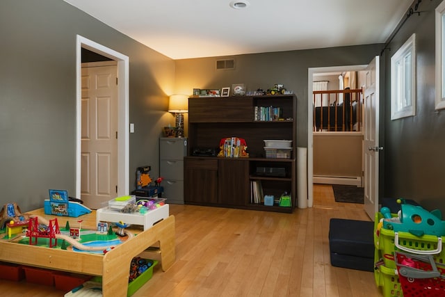 rec room featuring light wood-type flooring and a baseboard radiator