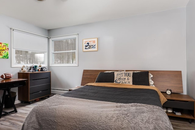 bedroom with light hardwood / wood-style floors and baseboard heating