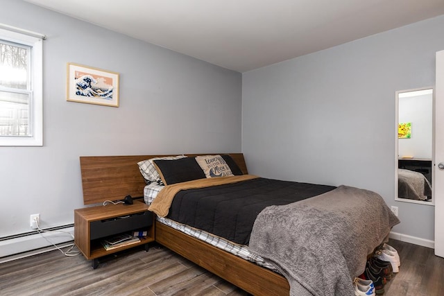 bedroom with dark hardwood / wood-style flooring and a baseboard heating unit