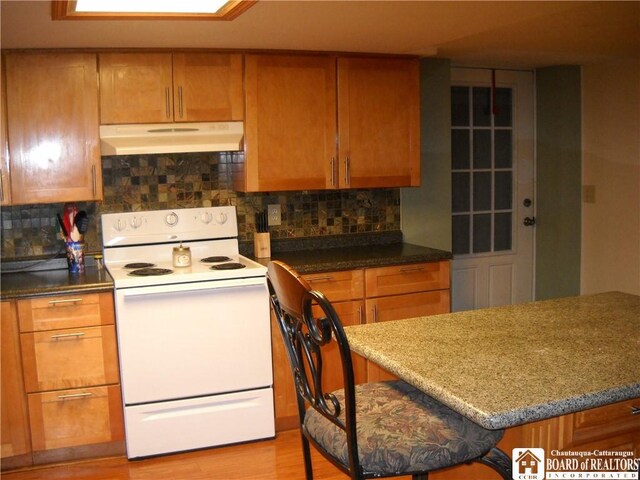 kitchen with tasteful backsplash, stone countertops, white electric range oven, and light wood-type flooring