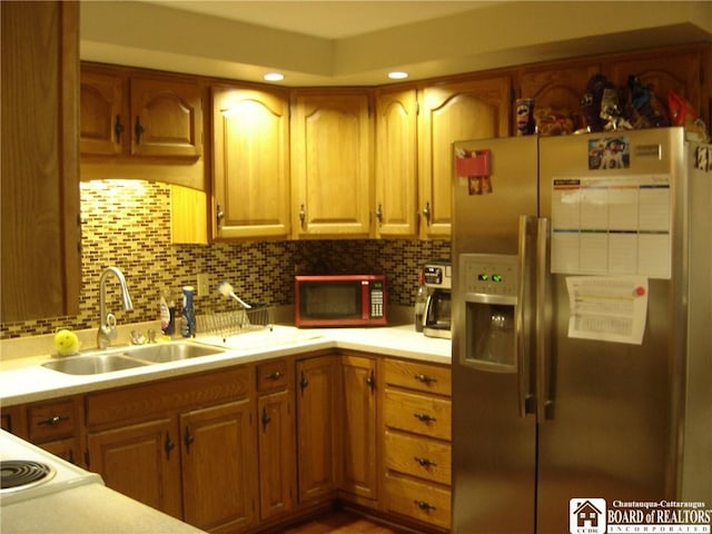 kitchen featuring cooktop, stainless steel refrigerator with ice dispenser, sink, and backsplash