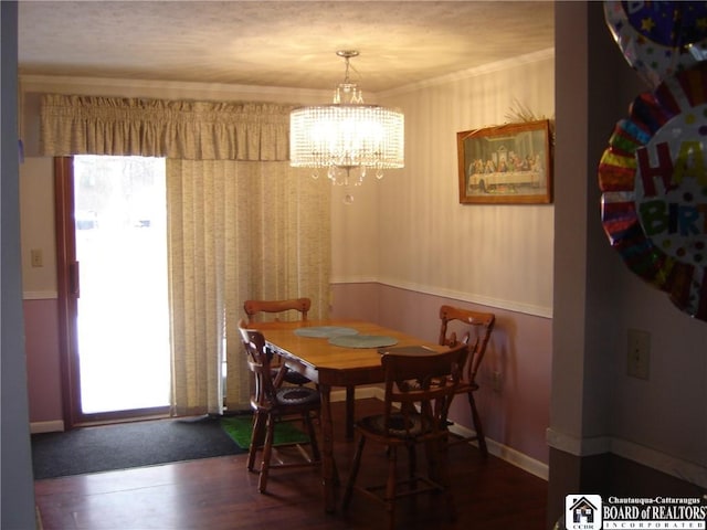 dining area with ornamental molding, dark wood-type flooring, and a notable chandelier