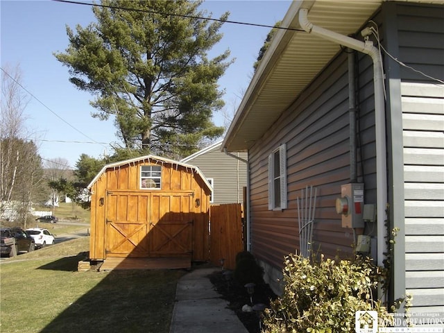 view of side of home featuring a storage unit, a lawn, and an outdoor structure