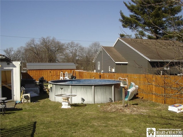 rear view of house featuring fence, a fenced in pool, a yard, an outdoor structure, and a storage unit