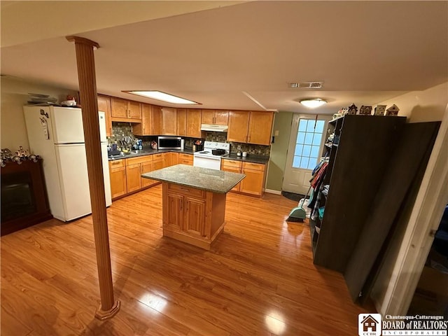 915 Prospect Ave, Olean-City, NY 14760 - kitchen with white appliances, under cabinet range hood, decorative columns, light wood-style flooring, and tasteful backsplash