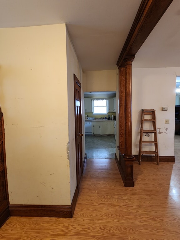 hallway with ornate columns and light wood-type flooring