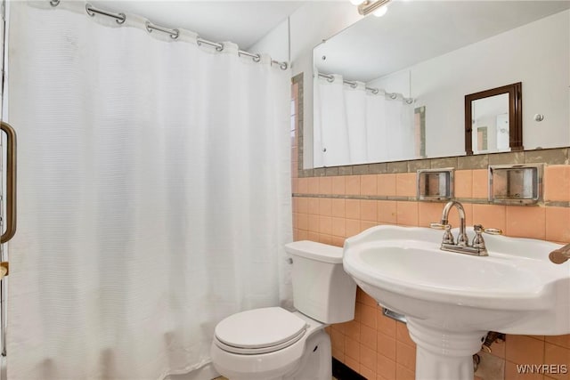 bathroom featuring walk in shower, toilet, and tile walls