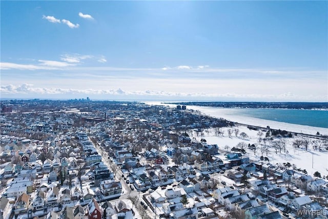 snowy aerial view featuring a water view and a beach view