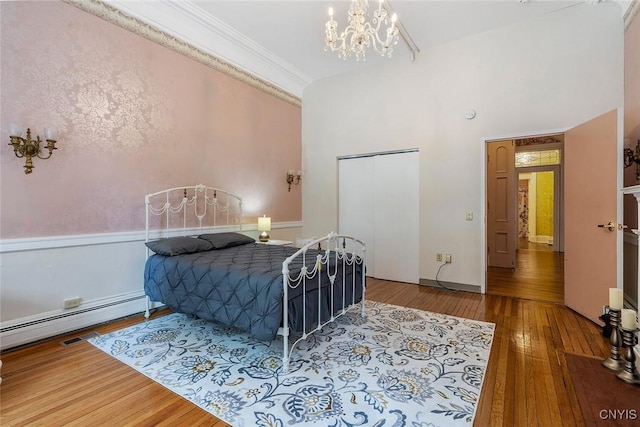 bedroom featuring hardwood / wood-style floors, crown molding, a baseboard radiator, and a notable chandelier