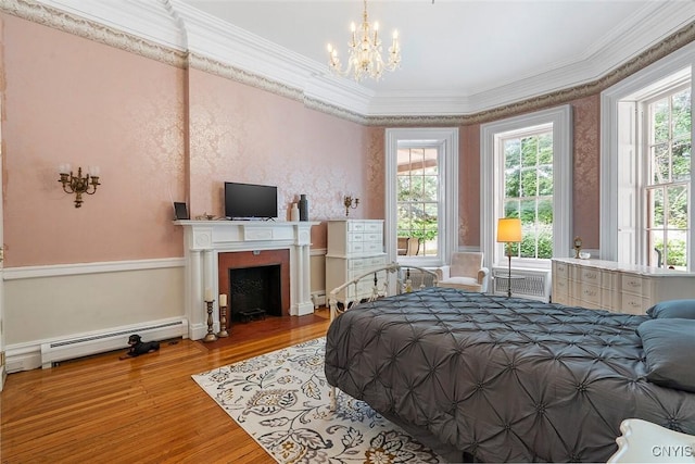 bedroom with a baseboard radiator, a notable chandelier, crown molding, and light hardwood / wood-style floors