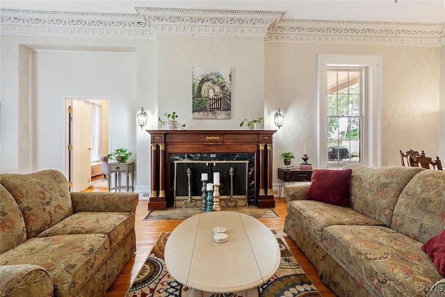 living room with wood-type flooring, crown molding, and a fireplace