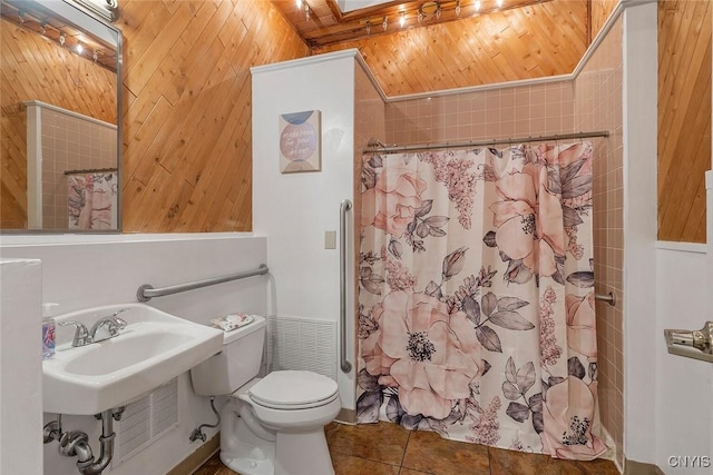 bathroom featuring lofted ceiling with skylight, toilet, wood walls, wood ceiling, and tile patterned flooring