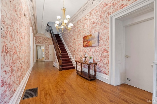 corridor featuring crown molding, a chandelier, and hardwood / wood-style floors