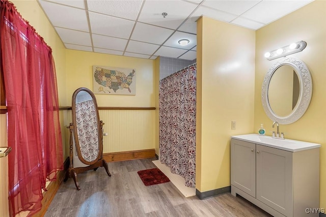 bathroom featuring hardwood / wood-style flooring, vanity, walk in shower, and a drop ceiling