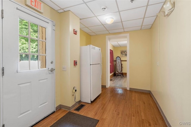 doorway to outside featuring a paneled ceiling and light hardwood / wood-style floors