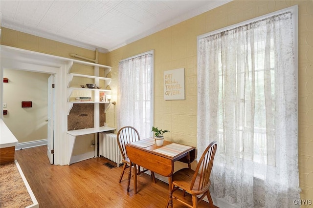 dining room with radiator, hardwood / wood-style flooring, and ornamental molding