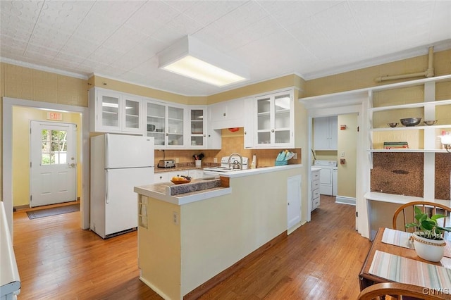 kitchen with white appliances, white cabinetry, ornamental molding, washing machine and clothes dryer, and light wood-type flooring