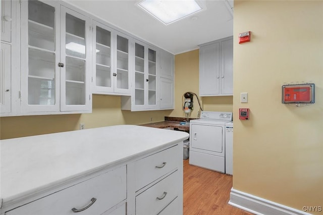 laundry room featuring independent washer and dryer, light hardwood / wood-style flooring, and cabinets