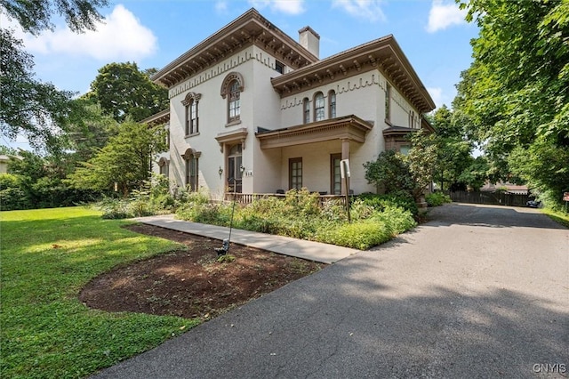 italianate-style house featuring covered porch and a front lawn