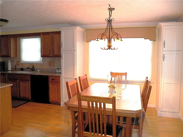 dining room with sink, crown molding, a notable chandelier, and light wood-type flooring