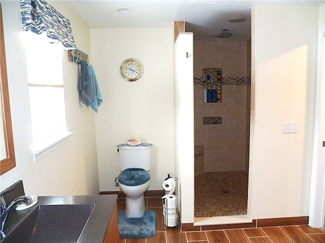 bathroom with tiled shower, toilet, and sink