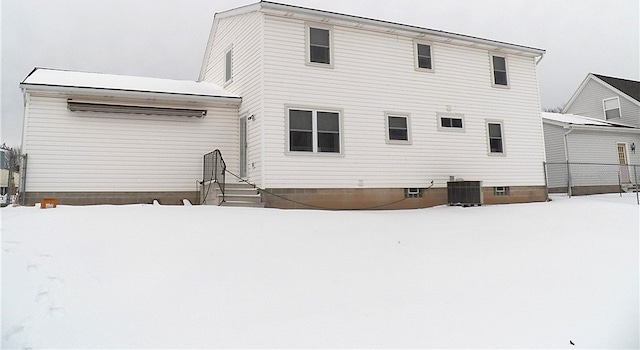 snow covered house featuring cooling unit