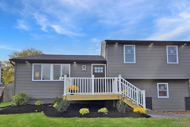 rear view of property featuring a lawn and a deck