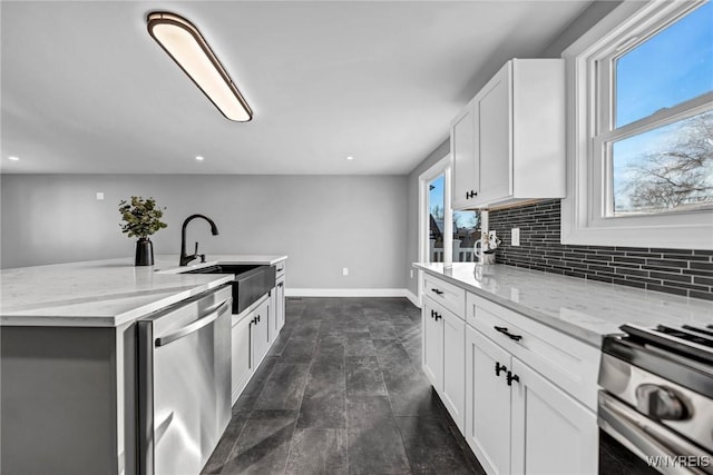 kitchen with sink, light stone countertops, white cabinets, and appliances with stainless steel finishes