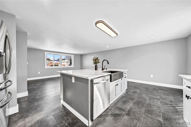 kitchen with white cabinetry, appliances with stainless steel finishes, a kitchen island with sink, and sink