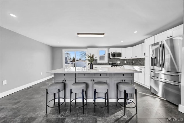 kitchen with stainless steel appliances, white cabinetry, a center island, and a kitchen breakfast bar