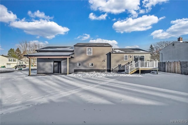 snow covered property featuring a wooden deck and a carport