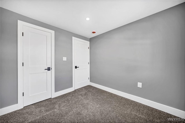 unfurnished room featuring dark colored carpet