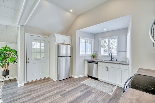 kitchen featuring sink, tasteful backsplash, appliances with stainless steel finishes, light hardwood / wood-style floors, and white cabinets