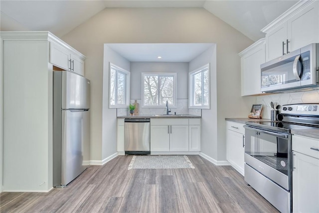 kitchen with white cabinetry, vaulted ceiling, and stainless steel appliances