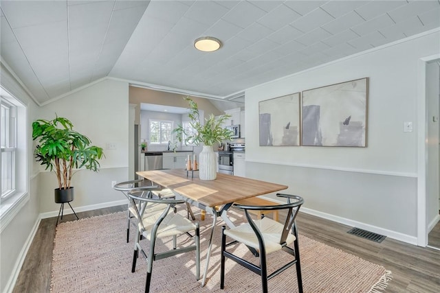 dining room featuring lofted ceiling, hardwood / wood-style floors, and crown molding